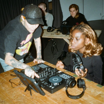 Tutor adjusting a controller for an attendee holding her headphones