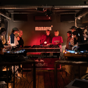 Two attendees playing back to back beneath the Manasia HUB sign