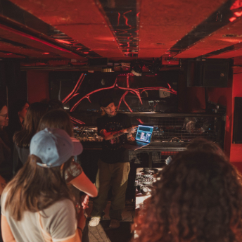 Tutor demonstrating on the decks while attendees watch in the red-lit Culture Box club
