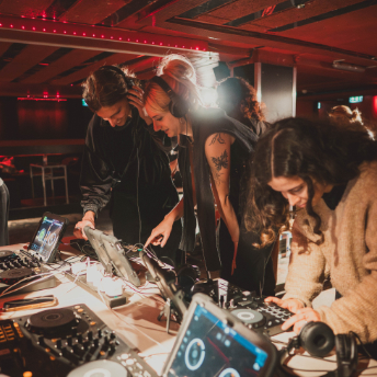 Attendees leaning over a workshop table of DJ equipment at Culture Box
