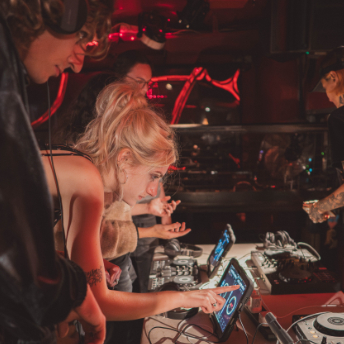 Attendee practising on a DJ controller under the club's red lighting