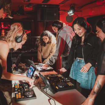 Tutor in headphones showing a group of attendees how to use the mixer