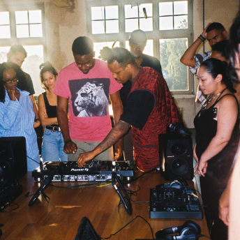 Attendee playing on the decks as the group watches in the House of Color loft