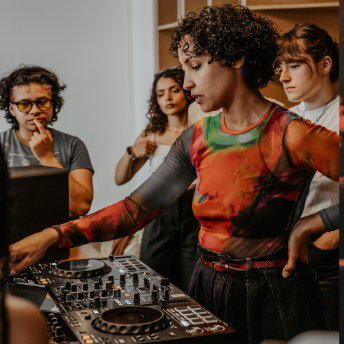 Attendee taking their turn on the decks as the group watches
