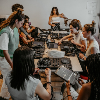Attendees seated around a table of DJ controllers at FFS, A-SIDE