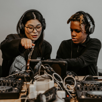 Two attendees in headphones working on a mix together