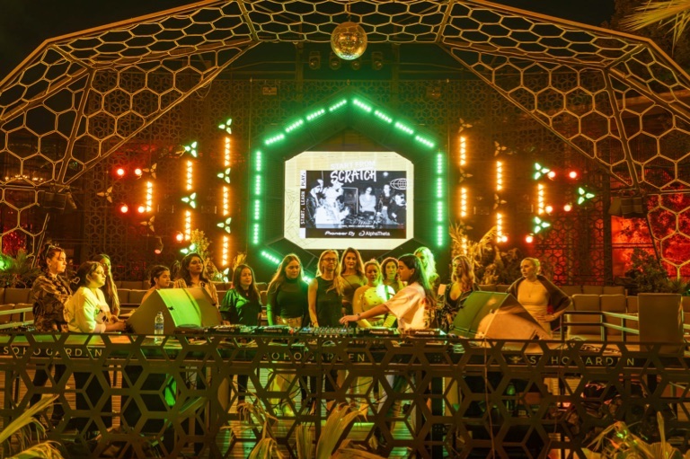 DJs performing in a club lit with green lights